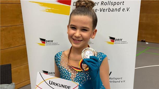 Leana Milane Behrmann hält ihre Bronzemedaille beim Ranglistenwettkampf in Duisburg in die Kamera.