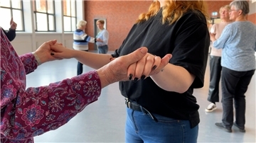 Zwei Personen halten sich beim Tanzen an den Händen