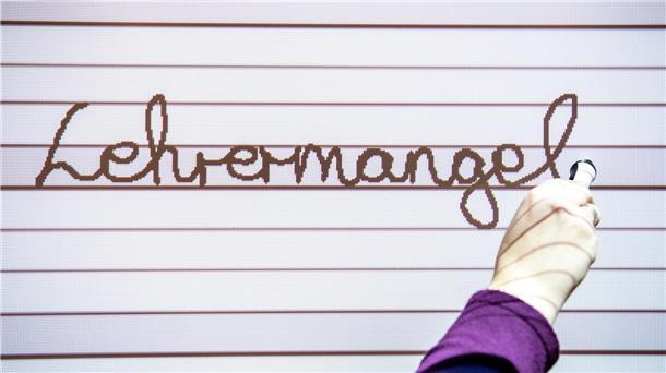 An ein Whiteboard wird der Schriftzug "Lehrermangel" geschrieben.