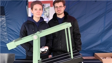 Ein Mann und eine Frau zeigen das Modell einer Brücke.