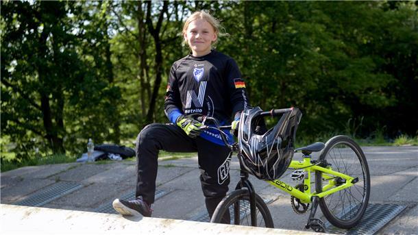 Ein Mädchen steht mit ihrem BMX-Rad am Starthügel.