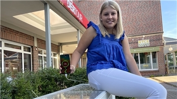 Leonie Näth, Auszubildende bei der Stadt Geestland, hat schon Probe gesessen: An der neuen Solarbank im Langener Lindenhof kann man ab sofort sein Handy laden - ganz einfach per USB oder Induktion.