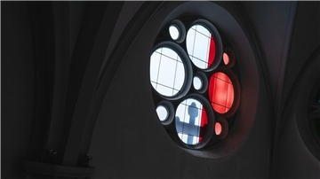 Licht wirft den Schatten eines Kreuzes durch ein Kirchenfenster.