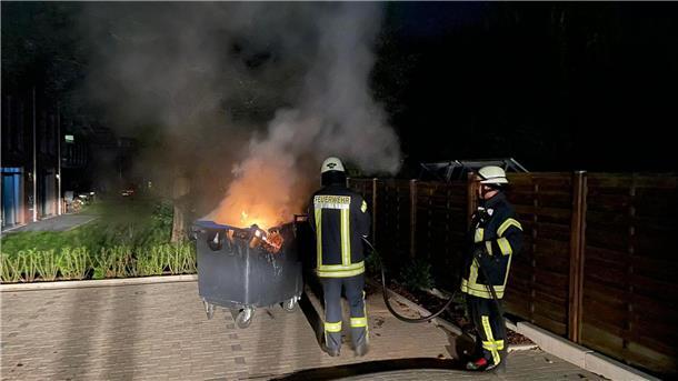 Feuerwehr löscht brennende Mülltonnen in der Nacht Lichterloh schlagen die Flammen aus der brennenden Mülltonne.