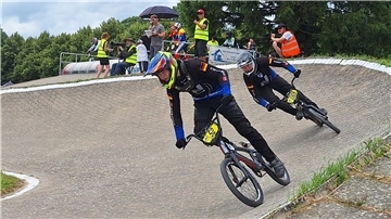 BMX-Fahrer liefern sich auf der Bahn einen Zweikampf.