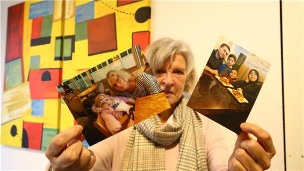 Eine Frau hält zwei Fotos hoch.