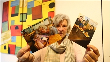 Eine Frau hält zwei Fotos hoch.