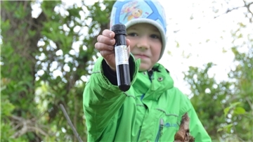 Linus begleitet seinen Vater oft beim Geocaching. Hier zeigt er eine Dose, die in einer Baumwurzel versteckt war.