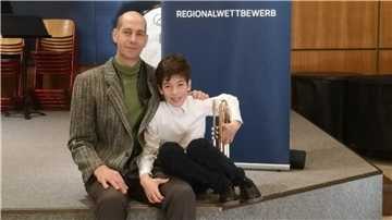 Lorenzo Boscolo mit seiner Trompete wird von Vater Gianpaolo Boscolo in den Arm genommen