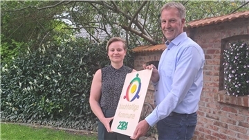 Luisa Wolter von der Kommunalen Umwelt-Aktion überreicht Beverstedts Bürgermeister Guido Dieckmann (parteilos) im Garten der Gaststätte Büttelmann in Wollingst die Auszeichnung als Nachhaltige Kommune. 