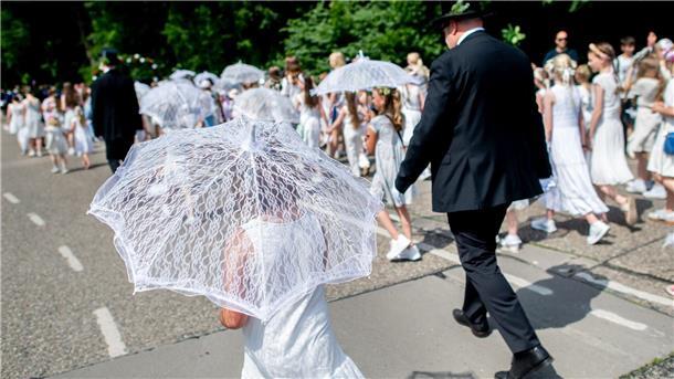 Mädchen laufen in weißen Kleidern beim Ausmarsch mit. 