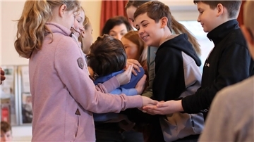 Mädchen und Jungen der KGS Tarmstedt fangen einen Mitschüler auf, der sich rückwärts von einem Tisch fallen lässt.