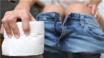 Eine Hand hält eine Rolle Klopapier und im Hintergrund sieht man den Hosenbund einer jeans