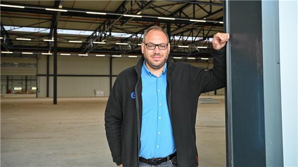 Ein Mann steht in der Einfahrt einer Halle. 