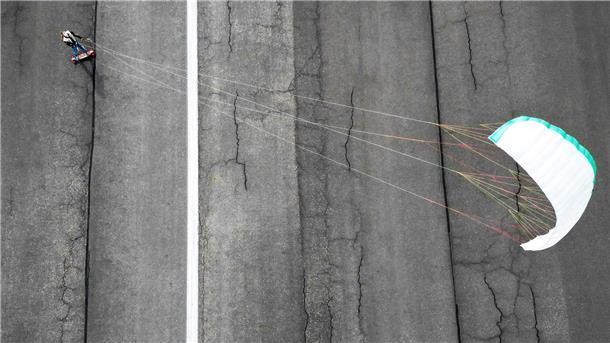 Man braucht nicht unbedingt Wasser: Ein Street-Kitesurfer fährt auf dem Tempelhofer Feld in Berlin entlang.