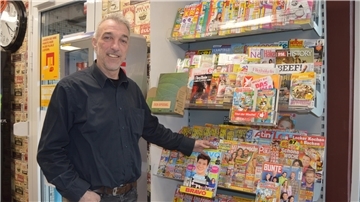 Ein Mann steht vor einem Magazin-Regal