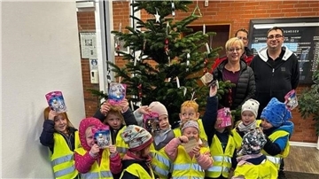 Manuela Manzke, Michael Lepies und Patrick Grimm freuen sich zusammen mit Kindern der Kita Regenbogen über die Weihnachtsbaumaktion.