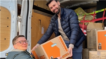 Zwei Bürger laden Hilfsgüter in einen Transporter.