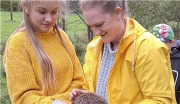 Maria schaut sich den Igel in Birthe Schlichters Hand aus der Nähe an, bevor er in die Freiheit entlassen wird.