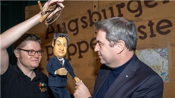 Markus Söder (r, CSU), Ministerpräsident von Bayern, gibt in der Augsburger Puppenkiste einer Söder-Marionette die Hand.