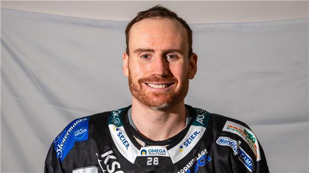 Eishockeyspieler im schwarzen Trikot vor weißer Wand