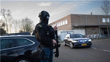 Maskierte und bewaffnete niederländische Polizisten bewachen einen Transport mit einigen der Verdächtigen, die vor dem Hochsicherheitsgebäude des Gerichts in Amsterdam eintreffen.