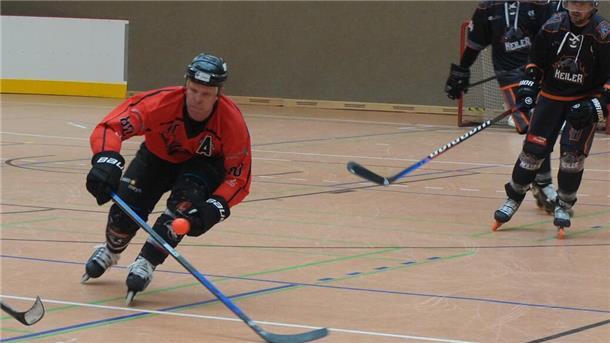 Ein Inlineskaterhockeyspieler fährt mit Schläger in der Hand.