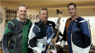 Drei männliche Sportschützen blicken in die Kamera.