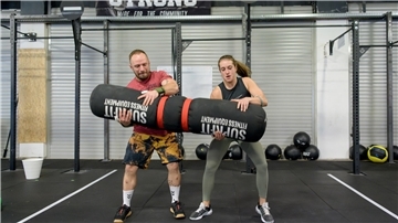 Maurice Monte und Jana Joy Vorrenhagen heben gemeinsam den „Wurm“ hoch, einen 50 Kilogramm schweren Sack. Solche Trainingsgeräte sind typisch für Crossfit.