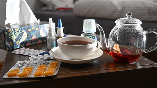 Medikamente und eine Kanne und Tasse Tee