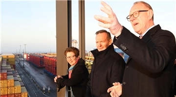 Drei Personen schauen von einem Balkon auf das Containerterminal