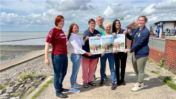 Gruppenfoto von sieben Personen, die drei Plakate für den 1. Butjenter Küstencrosslauf hochhalten