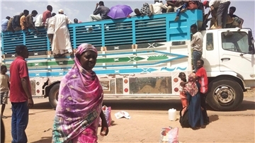 Menschen besteigen einen Lastwagen, um eine Stadt im Sudan zu verlassen.