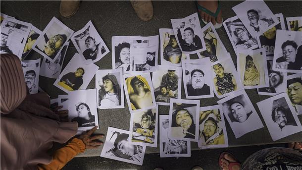Menschen, die nach ihren Angehörigen suchen, betrachten Fotos von Opfern der Fußballkrawalle, die ihnen von Freiwilligen zur Verfügung gestellt wurden, um ihnen bei der Identifizierung ihrer Familienangehörigen zu helfen.