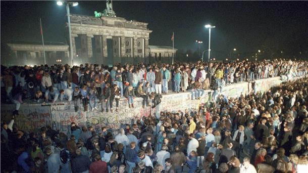 Menschen feiern am 9. November 1989 auf der Berliner Mauer vor dem Brandenburger Tor.
