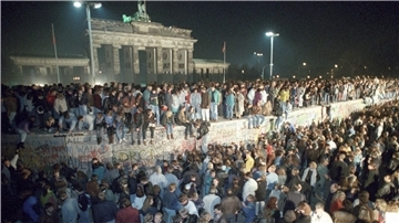 Menschen feiern am 9. November 1989 auf der Berliner Mauer vor dem Brandenburger Tor.
