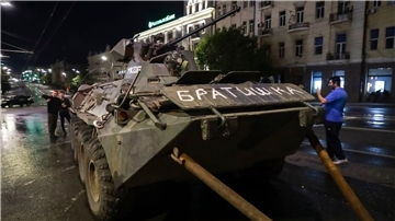 Menschen gehen um ein gepanzertes Fahrzeug des Militärunternehmens Wagner Group mit der Aufschrift „Brother“ herum, bevor sie ein Gelände am Hauptsitz des Südlichen Militärbezirks auf einer Straße in Rostow am Don verlassen.