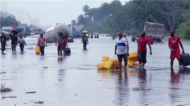 Menschen im nigerianischen Bayelsa waten durch überflutete Straßen.