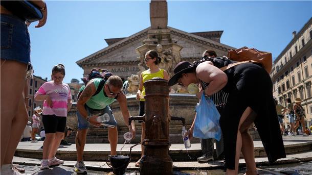 Menschen kühlen sich an einem Springbrunnen vor dem Pantheon in Rom ab.