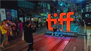 Menschen machen Fotos vor einer Leuchtreklame vor der TIFF Bell Lightbox während des 48. Toronto International Film Festivals.