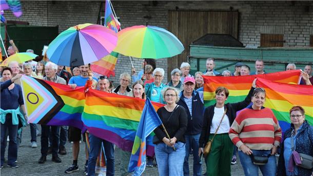 Menschen mit Regenbogenflaggen und -schirmen beteiligten sich an einer Kundgebung.