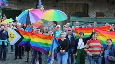 Menschen mit Regenbogenflaggen und -schirmen beteiligten sich an einer Kundgebung.