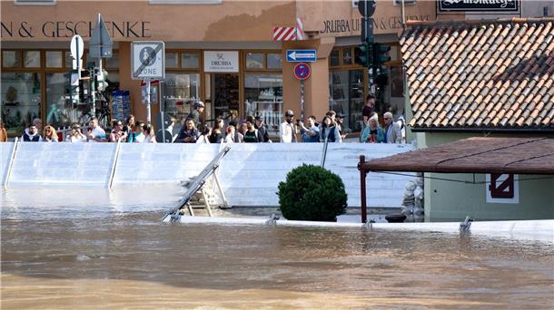 Bange Stunden an der Donau - Weitere Tote in Bayern entdeckt Menschen schauen sich in der Altstadt von Regensburg hinter einer Schutzwand das Hochwasser an.