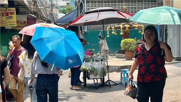 Rekord-Hitzewelle in Thailand führt zu mehr als 60 Toten Menschen schützen sich in Bangkok mit Schirmen vor der extremen Hitze und vor der Sonne.