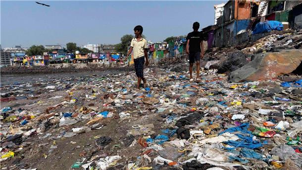 Verhandlungsrunde über UN-Plastikabkommen ohne Einigung Menschen spazieren am Strand des Badhwar Park im indischen Mumbai an Plastikmüll vorbei. (Archivbild)