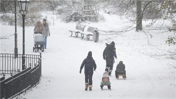 Menschen spazieren durch den verschneiten Volkspark Friedrichshain in Berlin.