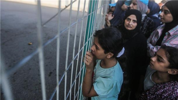 Menschen warten vor einem Zaun am Grenzübergang zwischen dem Gazastreifen und Ägypten.