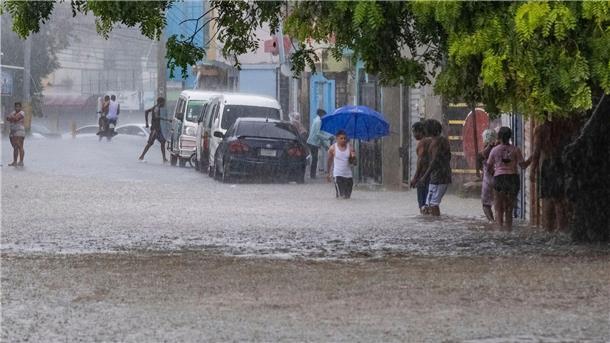 „Franklin“ fegt über Dominikanische Republik hinweg Menschen waten in Santo Domingo durch knietiefes Wasser auf einer Straße, die von den Regenfällen überflutet wurde.