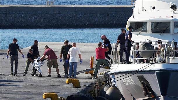 Migranten vor Griechenland ertrunken: Kinder unter Opfern Menschen werden nach der Rettungsaktion im Hafen von Mytilini auf Lesbos von Beamten der Küstenwache eskortiert.