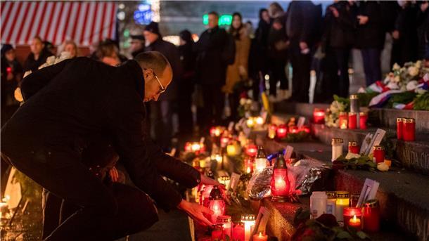 Menschen zünden bei der Gedenkveranstaltung zum Terroranschlag auf dem Berliner Breitscheidplatz an der Gedächtniskirche Kerzen an.